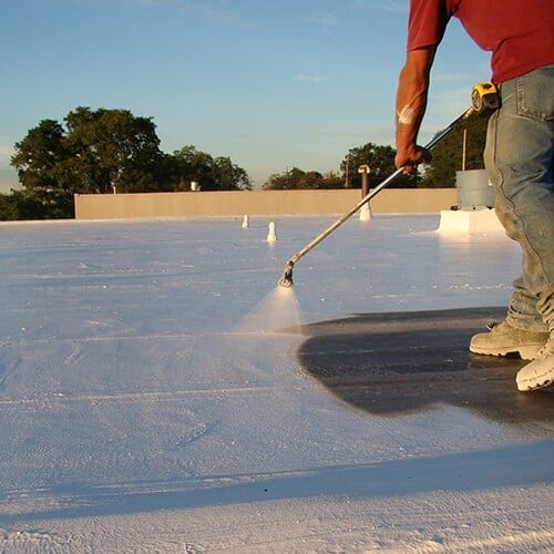 Roofer applies roof coating.