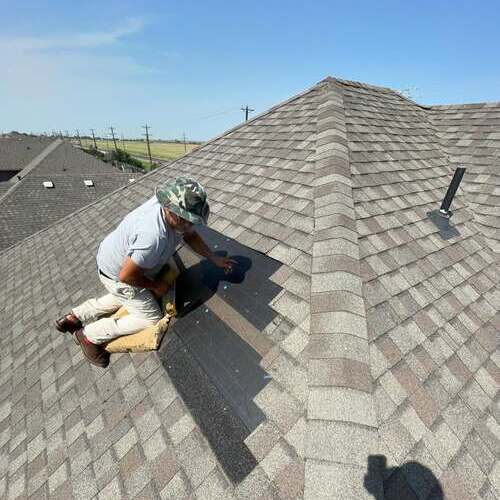 Roofer works on asphalt shingle roof.